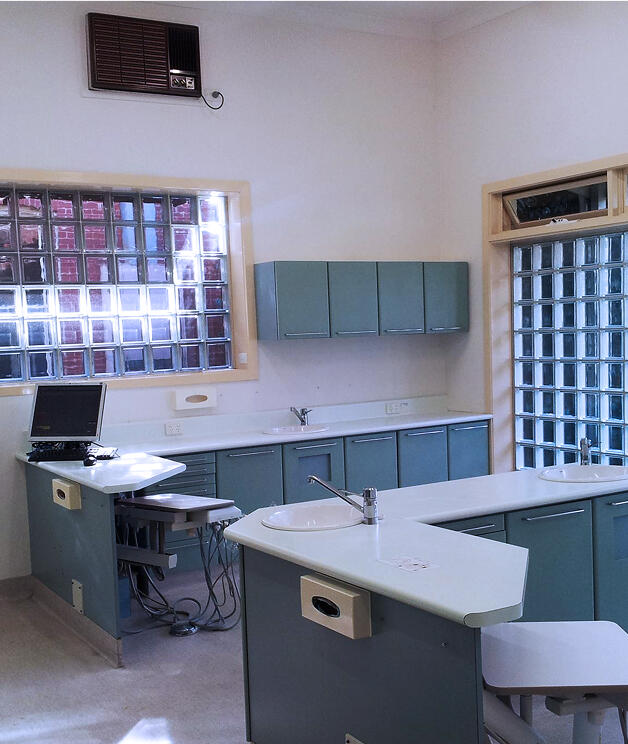Modern dental clinic room with treatment chair, sinks, and cabinetry