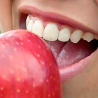 Healthy teeth biting a fresh apple symbolizing strong teeth and good dental health.
